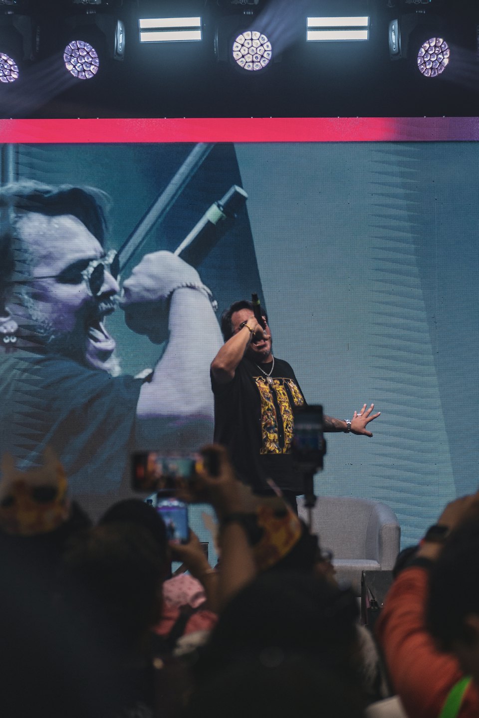 Performer speaks into a microphone on a concert stage.